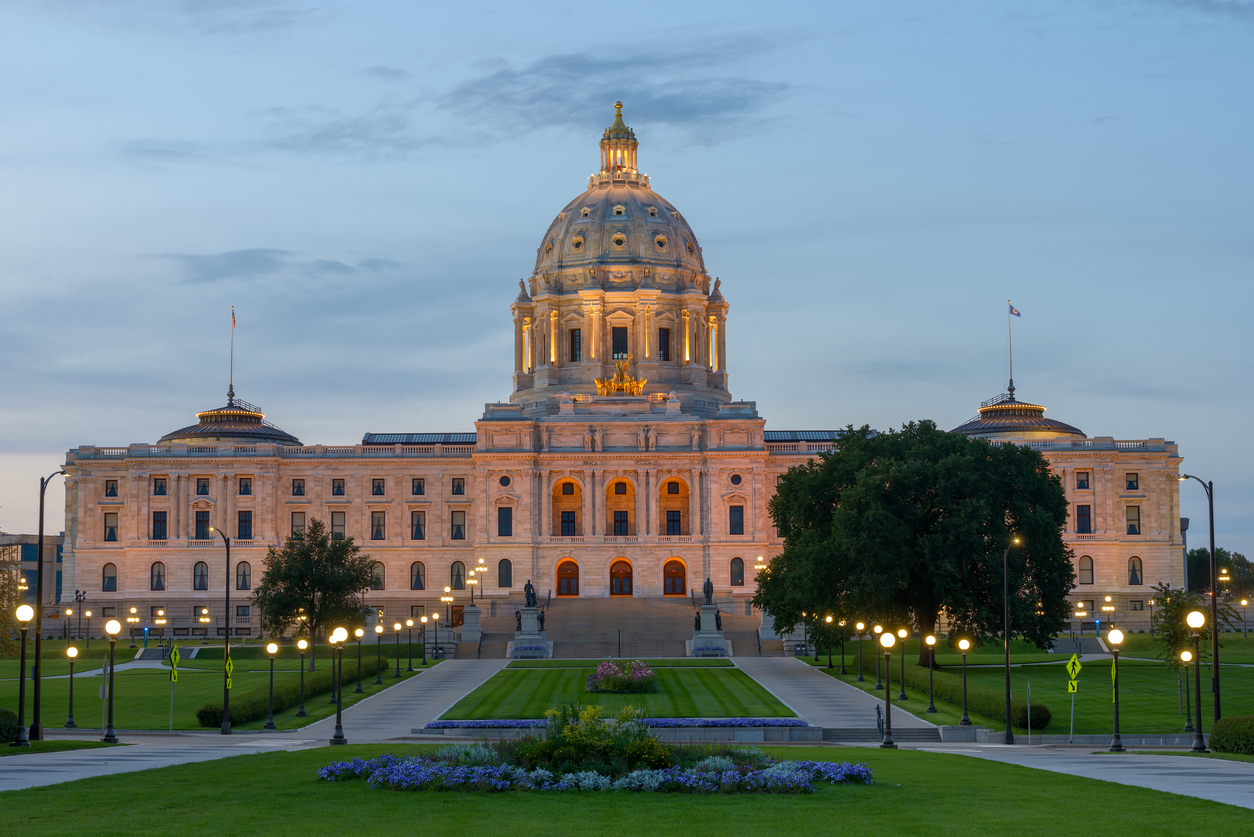 Facade of Minnesota Capitol building with lights on at dusk.